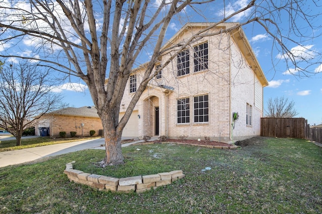 traditional-style home with brick siding, driveway, a front lawn, and fence