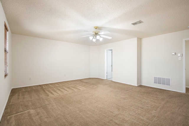 carpeted spare room featuring visible vents, ceiling fan, a textured ceiling, and baseboards