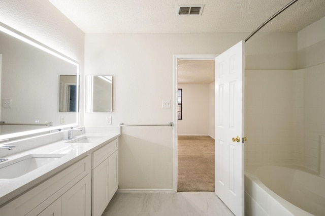 bathroom with visible vents, a sink, a textured ceiling, and double vanity