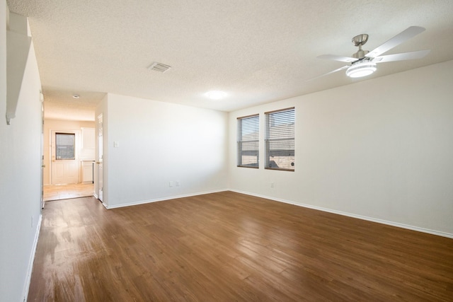 spare room with baseboards, a textured ceiling, visible vents, and dark wood-type flooring