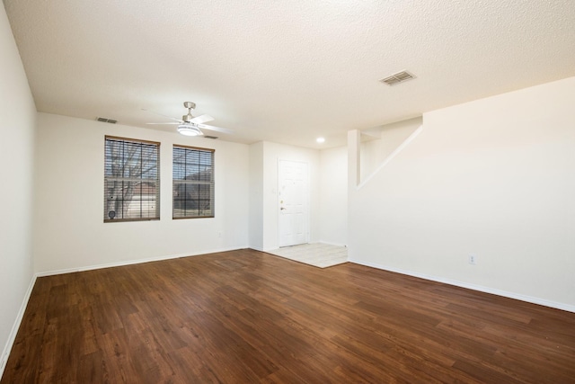 empty room with dark wood-style floors, baseboards, visible vents, and a textured ceiling