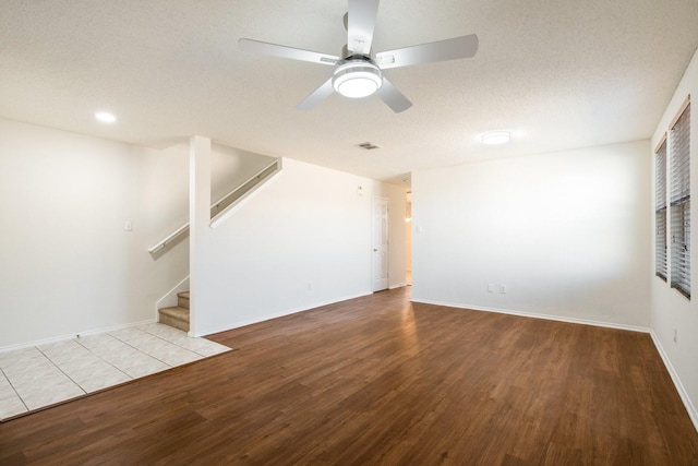 unfurnished living room with stairs, wood finished floors, a ceiling fan, and baseboards