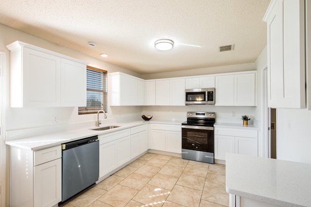 kitchen featuring appliances with stainless steel finishes, a sink, visible vents, and white cabinets