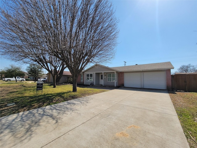 view of front of house featuring brick siding, an attached garage, a front yard, fence, and driveway