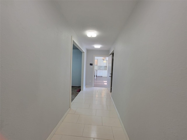 corridor featuring light tile patterned floors and baseboards