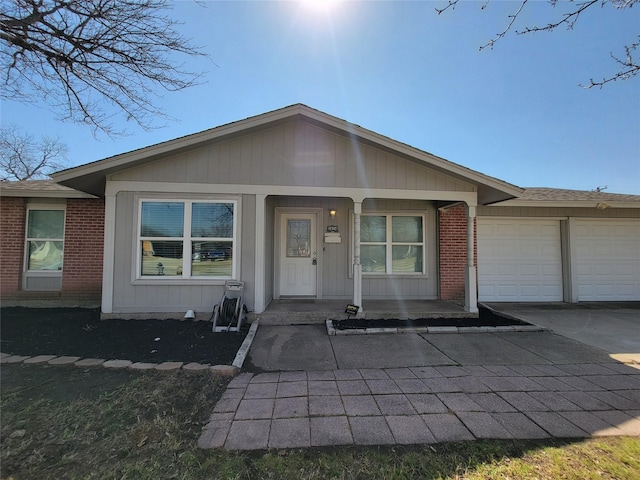 view of front of property with a porch, an attached garage, brick siding, a shingled roof, and driveway