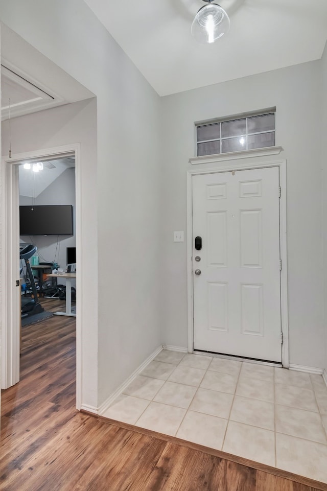 entrance foyer with lofted ceiling, light tile patterned floors, and baseboards