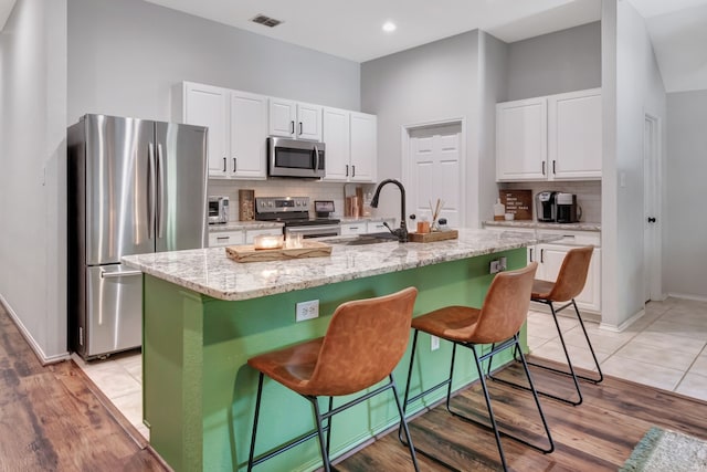 kitchen featuring stainless steel appliances, visible vents, a sink, and white cabinetry