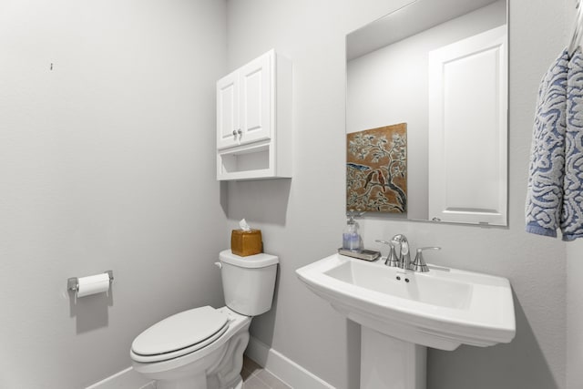 bathroom featuring toilet, baseboards, and a sink