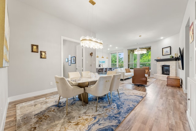 dining area featuring recessed lighting, an inviting chandelier, a glass covered fireplace, wood finished floors, and baseboards