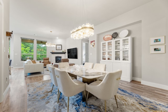 dining room featuring light wood-style floors, a brick fireplace, and baseboards