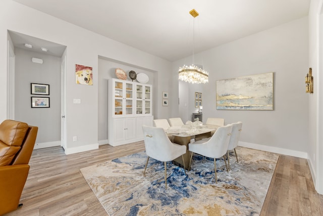 dining space featuring an inviting chandelier, light wood-style flooring, and baseboards