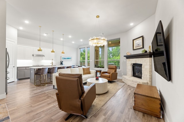 living room featuring light wood-style floors, recessed lighting, baseboards, and a stone fireplace