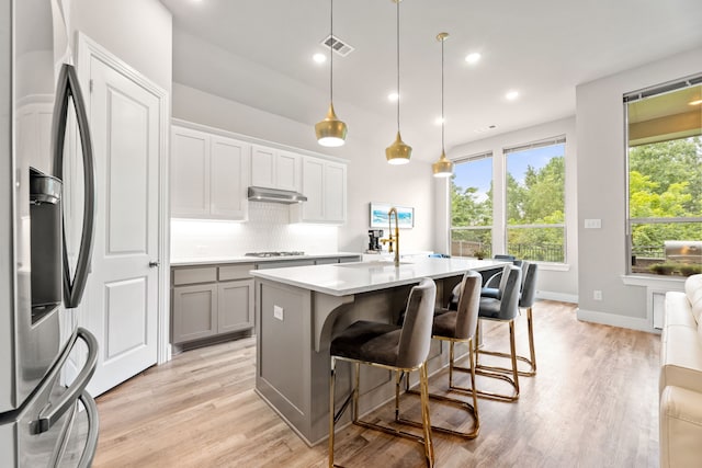 kitchen featuring tasteful backsplash, visible vents, appliances with stainless steel finishes, light wood-type flooring, and a sink