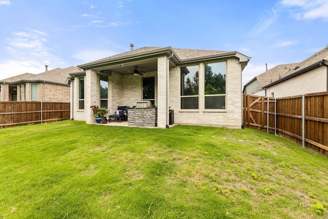 back of property featuring a yard, a fenced backyard, brick siding, and a ceiling fan