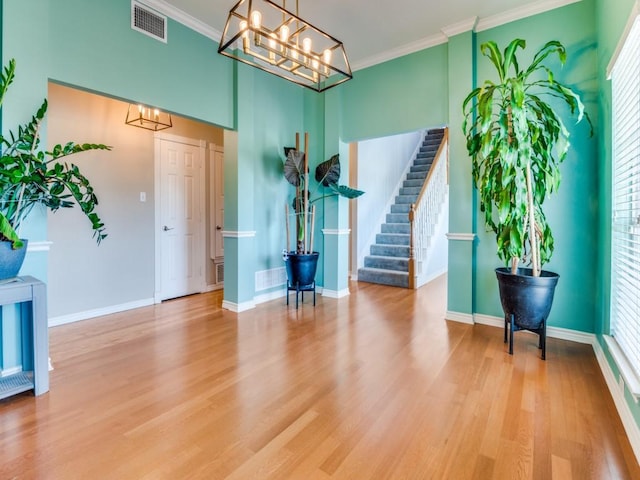 entryway with visible vents, crown molding, light wood-style flooring, and stairs