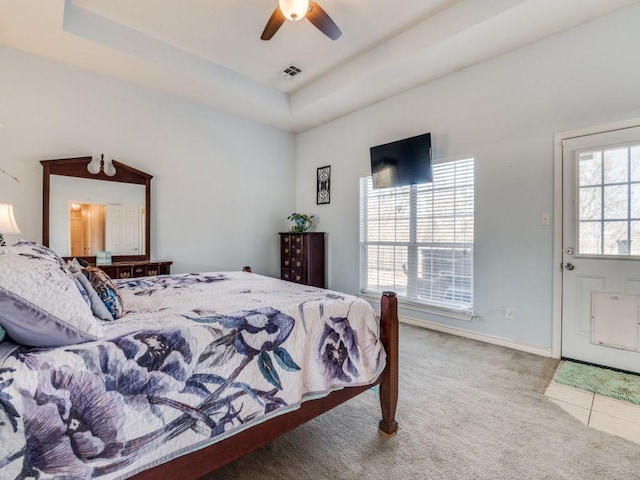 tiled bedroom featuring a tray ceiling, multiple windows, carpet, and visible vents