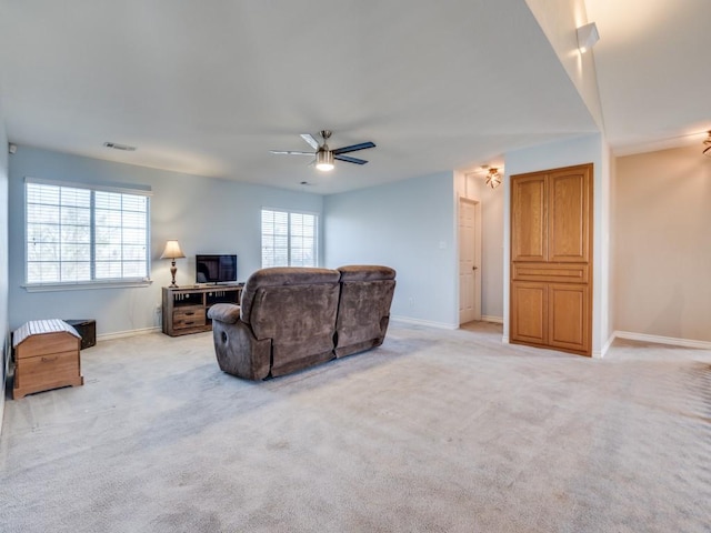 living area featuring a ceiling fan, light colored carpet, visible vents, and baseboards