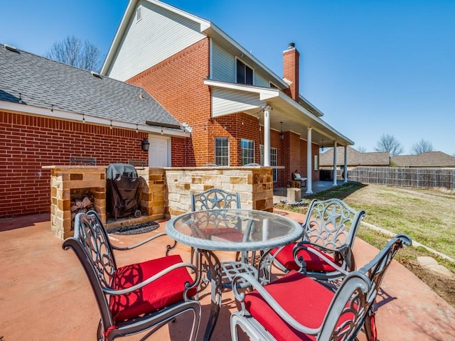 view of patio with outdoor dining space, grilling area, and fence