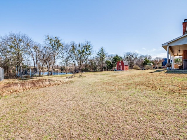 view of yard with an outbuilding, a shed, a trampoline, and a water view