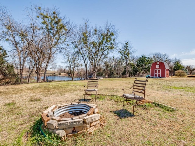 view of yard featuring an outdoor fire pit, an outdoor structure, fence, and a water view