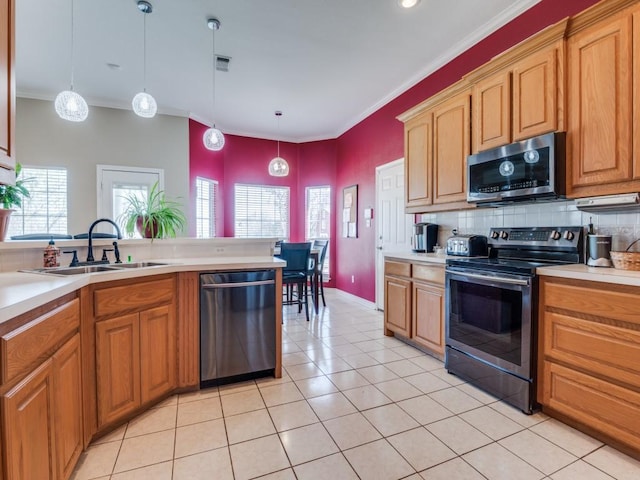 kitchen with light tile patterned floors, light countertops, decorative backsplash, appliances with stainless steel finishes, and a sink