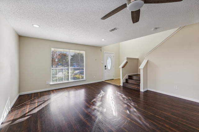 unfurnished living room featuring a textured ceiling, wood finished floors, visible vents, baseboards, and stairway