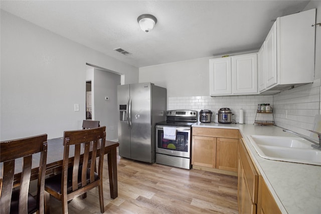 kitchen with visible vents, light wood-style flooring, stainless steel appliances, light countertops, and a sink