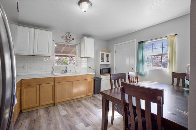 kitchen featuring light countertops, light wood-style flooring, freestanding refrigerator, a sink, and black microwave