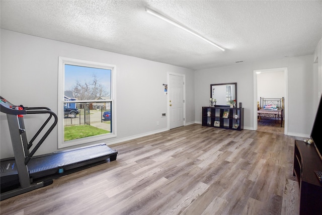 exercise room with a textured ceiling, baseboards, and wood finished floors