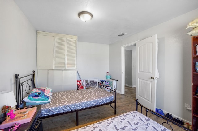 bedroom featuring wood finished floors, visible vents, and baseboards