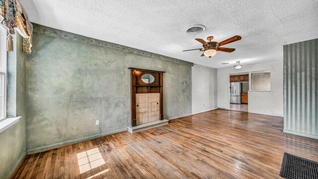 unfurnished room featuring baseboards, visible vents, wood-type flooring, and ceiling fan