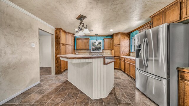 kitchen with a center island, stainless steel fridge with ice dispenser, light countertops, brown cabinets, and a sink