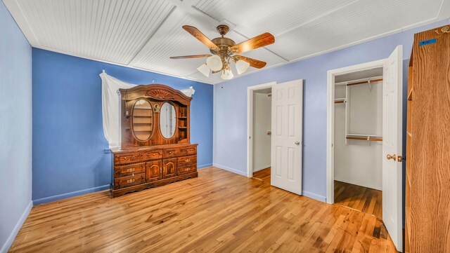 unfurnished bedroom with a closet, baseboards, wood finished floors, and a ceiling fan