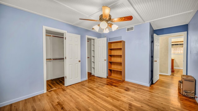 unfurnished bedroom featuring a closet, visible vents, baseboards, and hardwood / wood-style floors