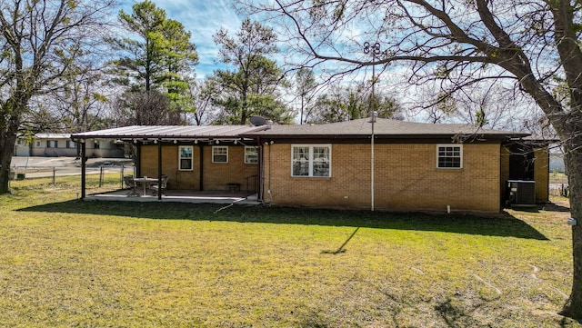 rear view of property featuring brick siding, central AC unit, a lawn, and a patio