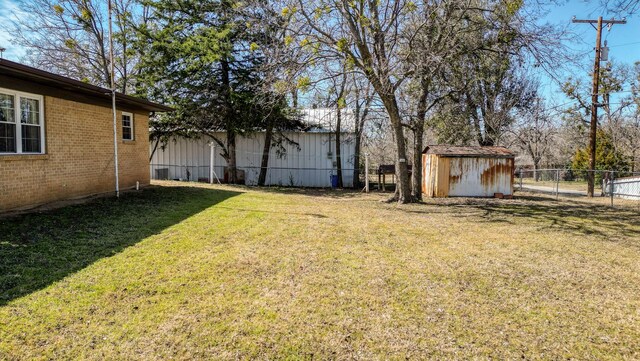 view of yard featuring an outbuilding, a shed, and fence