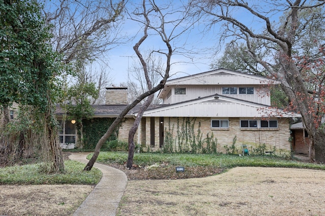 view of front of house with brick siding and a chimney