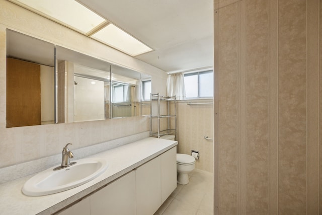 bathroom with toilet, vanity, and tile patterned flooring