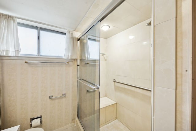 bathroom with wallpapered walls, a shower stall, and toilet