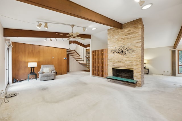 living area featuring lofted ceiling with beams, wooden walls, stairs, and a fireplace