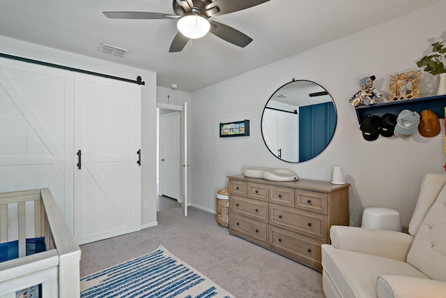 bedroom featuring a barn door, carpet flooring, a ceiling fan, visible vents, and baseboards