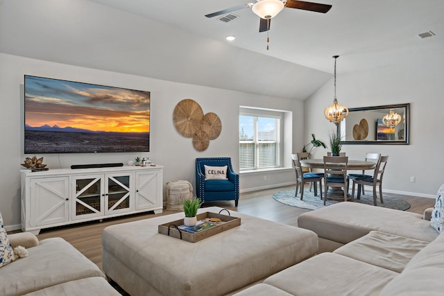 living room featuring visible vents, vaulted ceiling, and wood finished floors