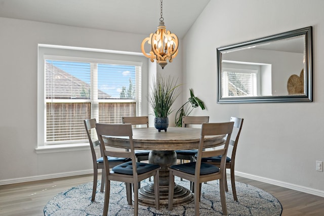 dining area featuring lofted ceiling, an inviting chandelier, baseboards, and wood finished floors