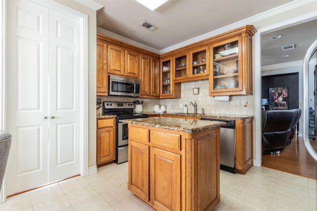 5033 Southpoint Dr, Arlington, TX 76017 - kitchen featuring appliances with stainless steel finishes, brown cabinetry, light stone countertops, crown molding, and a sink