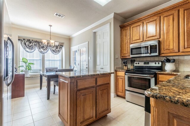 5033 Southpoint Dr, Arlington, TX 76017 - kitchen featuring appliances with stainless steel finishes, a chandelier, brown cabinetry, light tile patterned floors, and ornamental molding