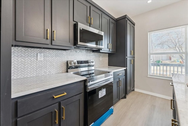 kitchen featuring baseboards, decorative backsplash, appliances with stainless steel finishes, light wood-style floors, and recessed lighting