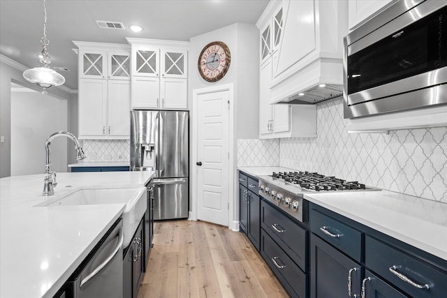 kitchen with pendant lighting, stainless steel appliances, light countertops, visible vents, and white cabinets