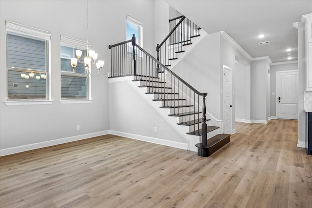 stairway featuring visible vents, baseboards, ornamental molding, wood finished floors, and an inviting chandelier