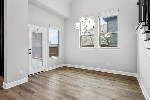 unfurnished dining area with a notable chandelier, baseboards, and wood finished floors